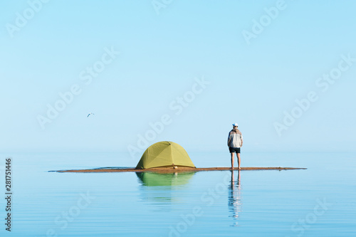 A man on the island with a tent. Man in focus, background blurred