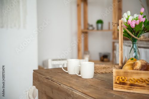 Bread in a textured wooden box in the kitchen in a rustic style. Breakfast  bread  white cups in the interior of bright Scandinavian cuisine.