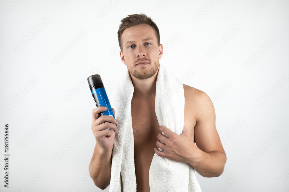 handsome young man with white towel on his shoulders holding shaving foam in his hand on isolated white background handsome young man with white towel on his shoulders holding shaving foam in his hand on isolated white background