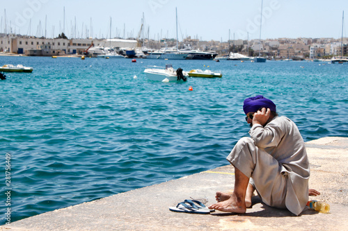 persona sentada junto al mar hablando por el movil. © hdserch