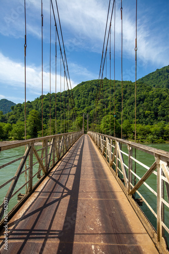 Old metal bridge over river in mountains valley