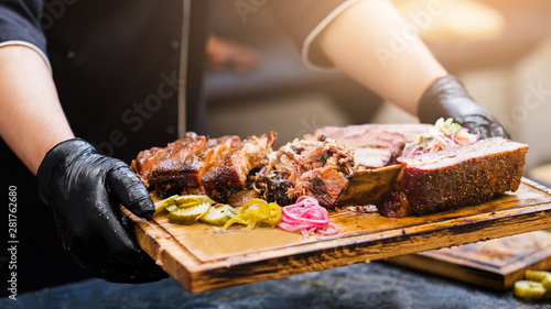 Professional catering. Cropped shot of chef holding wooden board with smoked meat assortment.