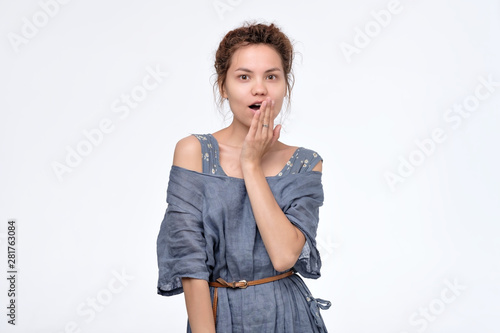 Surprised shocked asian young woman keeps mouth widely opened, looks confused as she does not believe gossip. Studio shot