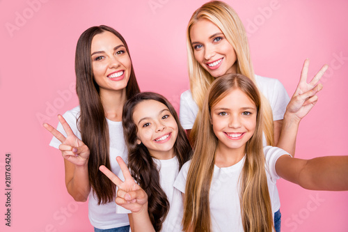 Self-portrait of four nice-looking attractive lovely charming cute glad cheerful cheery optimistic long haired girls having fun showing v-sign isolated over pink pastel background
