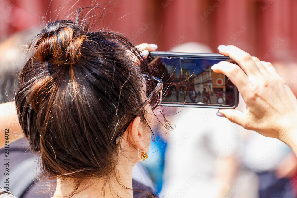 Fototapeta premium Woman takes a photo on the modern smartphone on Red Square in Moscow at sunny summer day closeup