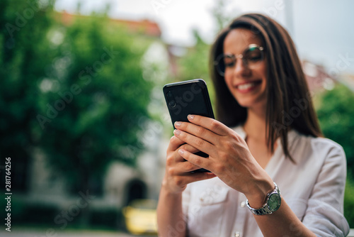 Young cheerful woman using smart phone, focus on hands.