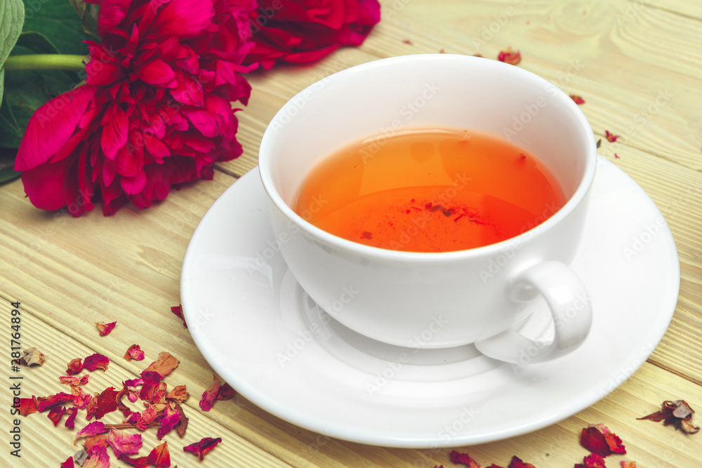 Cup of green tea on table with fresh peony flowers Cup of green tea on table with fresh peony flowers