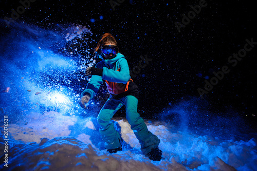 Photography Active female snowboarder dressed in a orange and blue sportswear riding on the