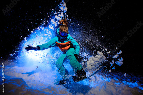 Active female snowboarder dressed in a orange and blue sportswear jumping on the snow