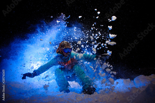 Female snowboarder dressed in a orange and blue sportswear makes tricks on the snow © fesenko