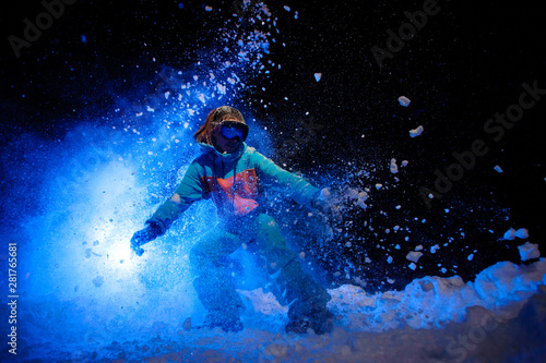Active female snowboarder dressed in a orange and blue sportswear making tricks on the snow