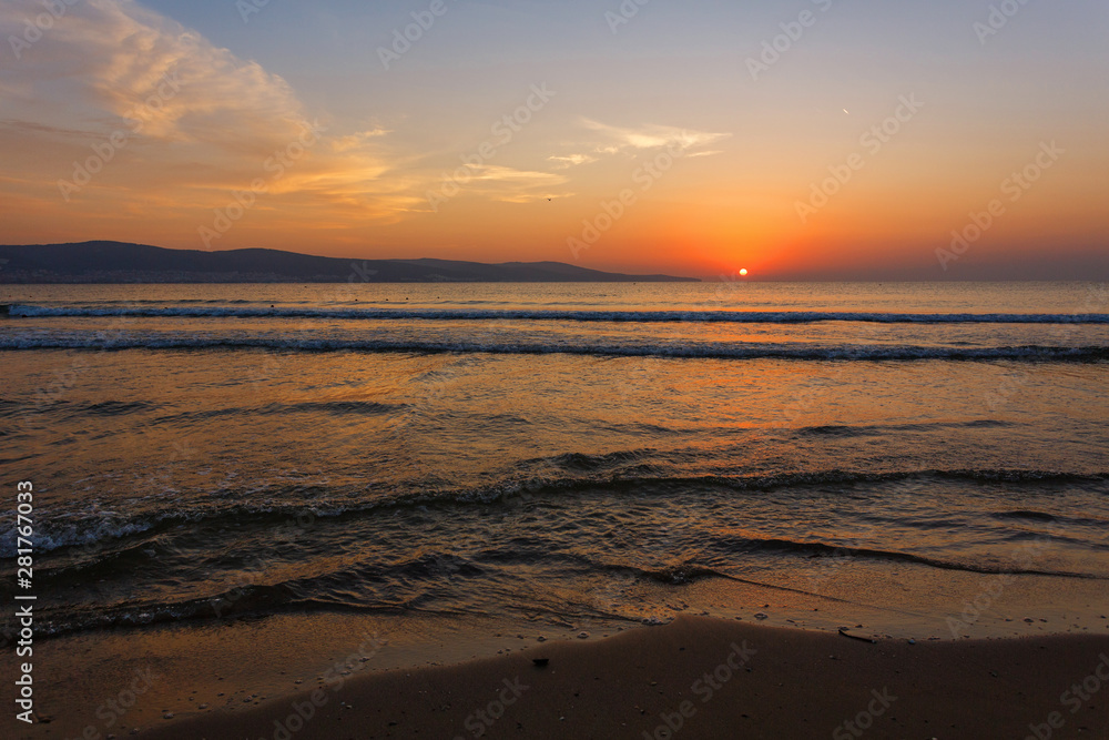 The sun sits behind the horizon. Summer landscape. Warm evening on the seashore.