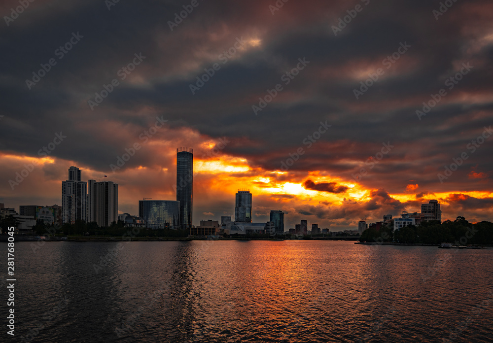 Cloudy sunset over Yekaterinburg business center reflecting in water of pond