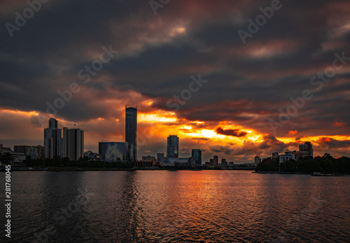 Cloudy sunset over Yekaterinburg business center reflecting in water of pond