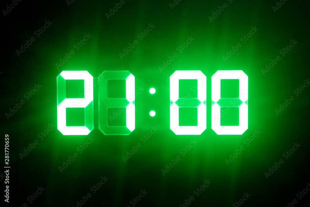 Green glowing digital clocks in the dark show 21:00 time Green glowing digital clocks in the dark show 21:00 time