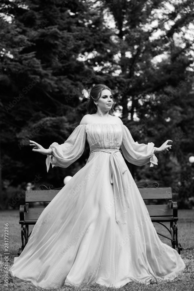 Fashion photo of beautiful woman with  in elegant dress. Woman in long flying evening dress.  Elegant hairstyle and makeup. Black and white. 
