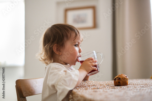 curly-haired Toddler girl drinks compote