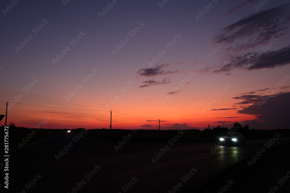 Sunset noir in country with car headlights in black foreground