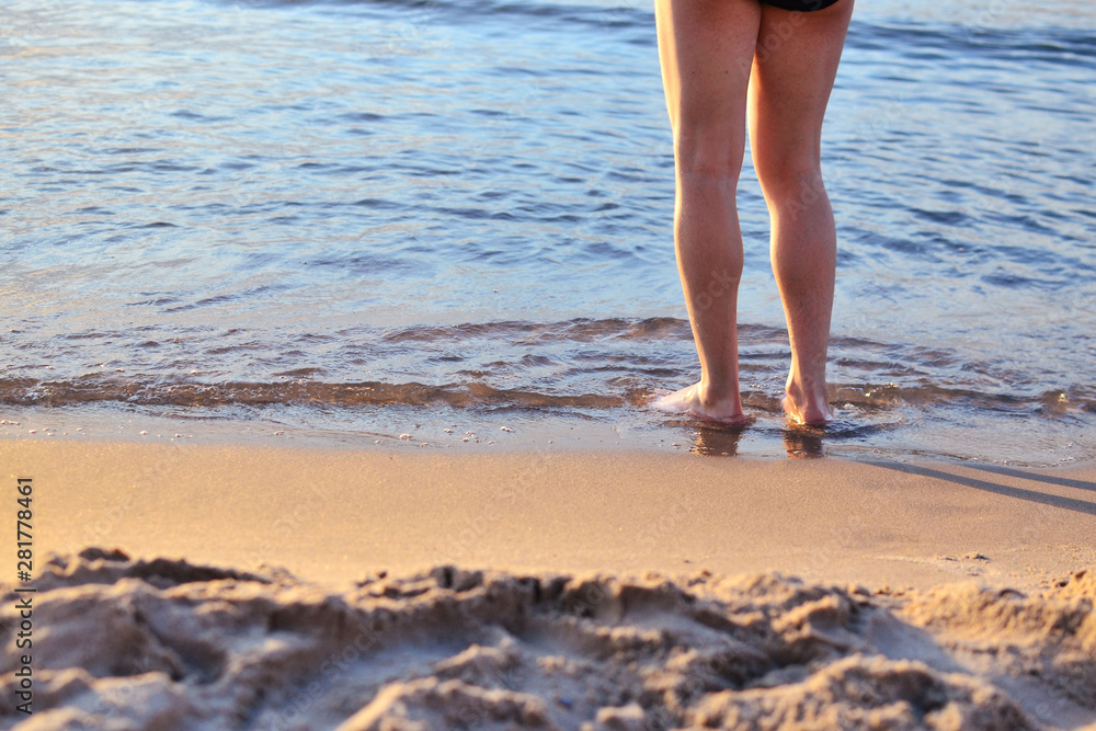 a man stands on the sand by the sea, the legs of a man in the sand a man stands on the sand by the sea, the legs of a man in the sand