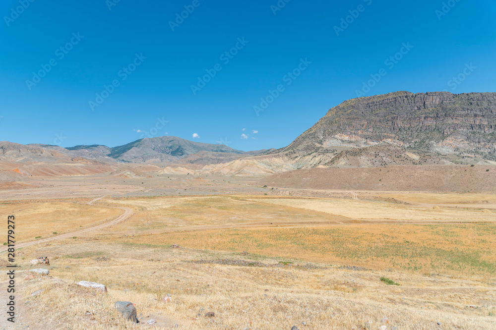 Panoramic view on the yellow field with dry grass and rock and mountains.