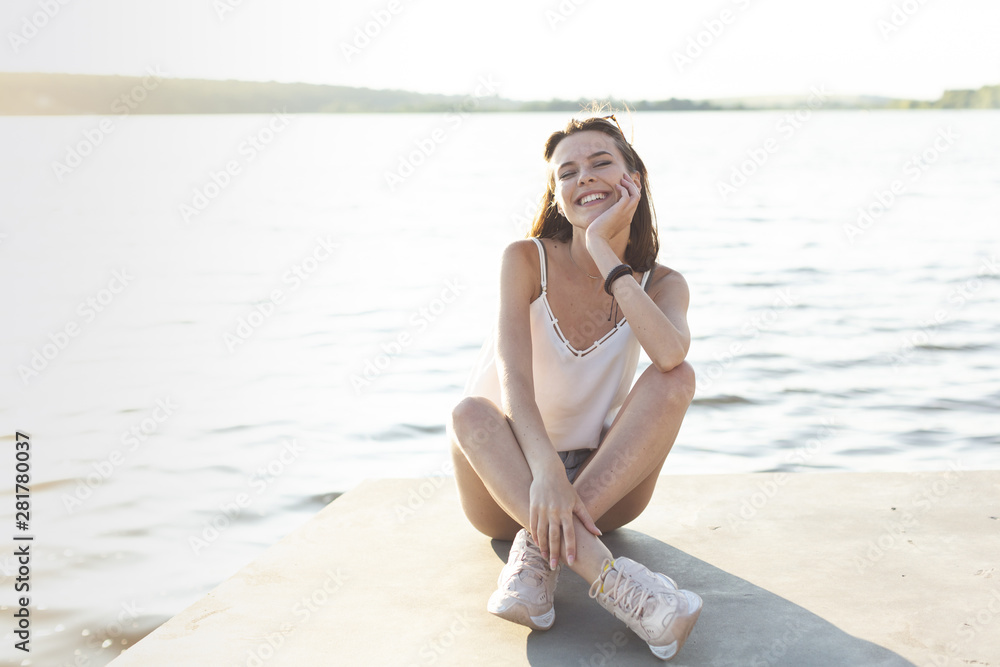 Woman posing with her eyes closed next to a lake Woman posing with her eyes closed next to a lake
