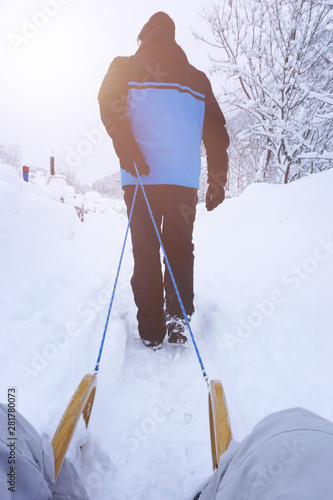 ein Mann zieht im Winter einen Schlitten, viel Schnee, Schlittenfahrt, Winterurlaub
