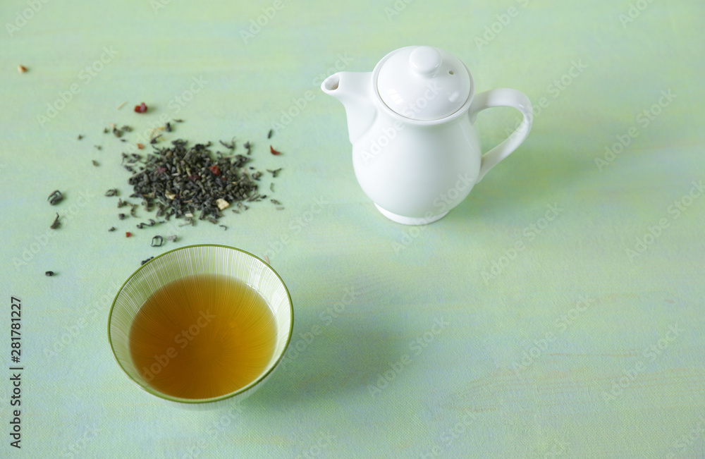green tea in a bowl with a teapot and loose tea on a light green surface. It is a rich source of antioxidants and polyphenols. A healthy drink for health and vitality. Top view. green tea in a bowl with a teapot and loose tea on a light green surface. It is a rich source of antioxidants and polyphenols. A healthy drink for health and vitality. Top view.