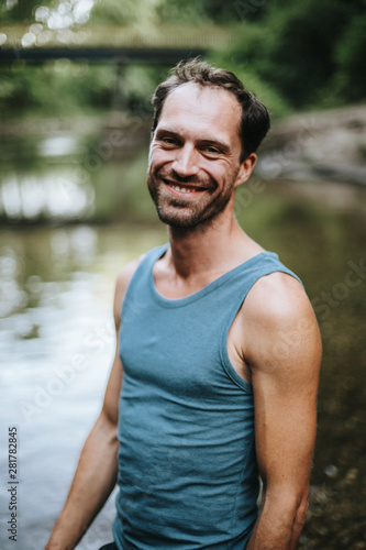 portrait of smiling man standing in the middle of a river