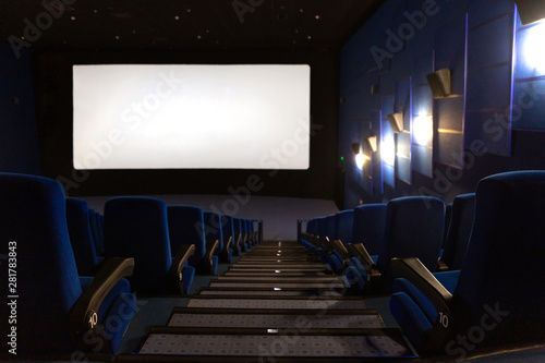 Blue cinema auditorium with blank empty white screen.
