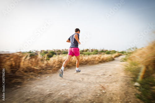 Caucasian young man running on a seacost path on a lovely summer evening, training for marathon (motion blurred image). © lightpoet