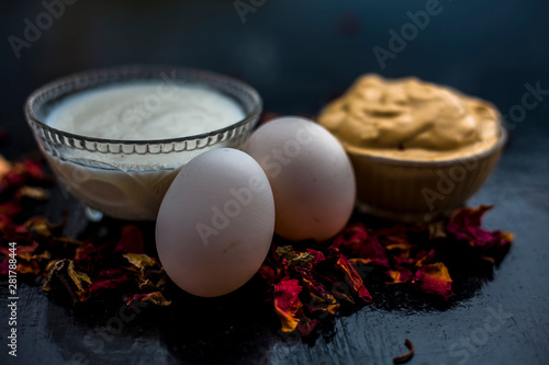 Best DIY face mask of multani mitti or mulpani mitti along with egg white and some yogurt well mixed in a glass bowl on the black wooden surface for the remedy of even skin. photo