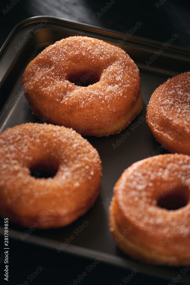 White sugar donuts on a sheet metal tray