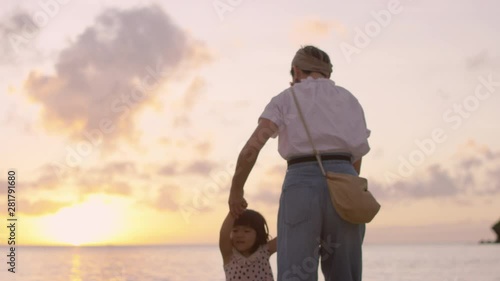 Mother with¬†daughter¬†walking in sea at sunset photo