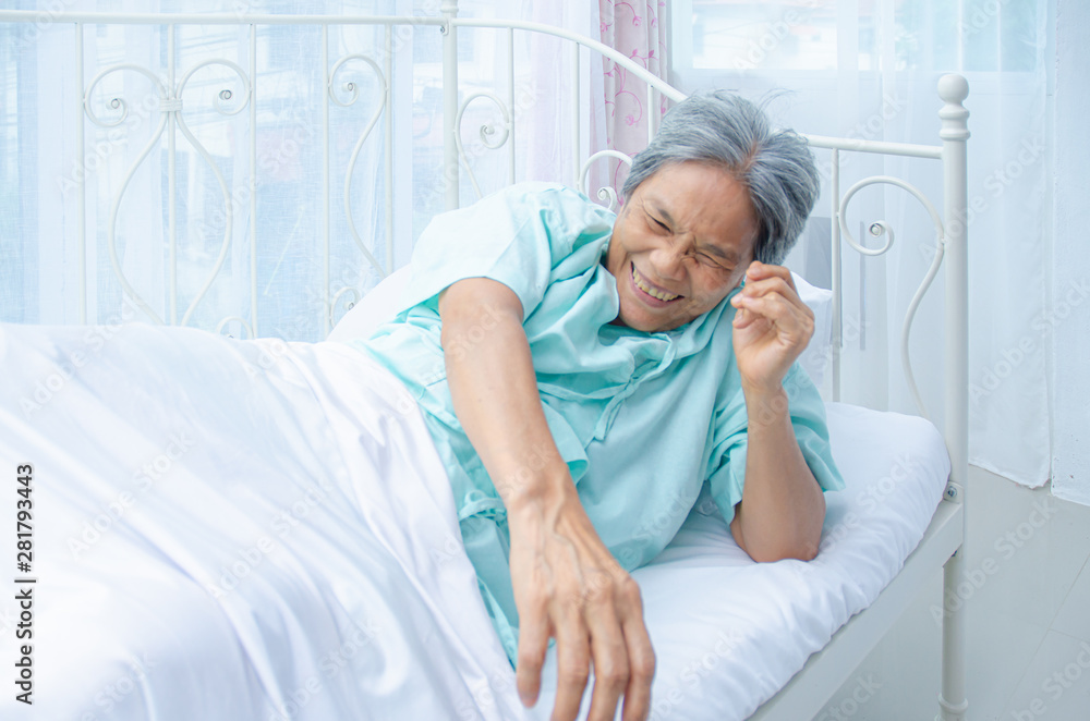 Obraz premium An old Asian woman wearing a green shirt Sleeping on the bed in the room. Elderly people are not comfortable. Women have white hair on their heads.