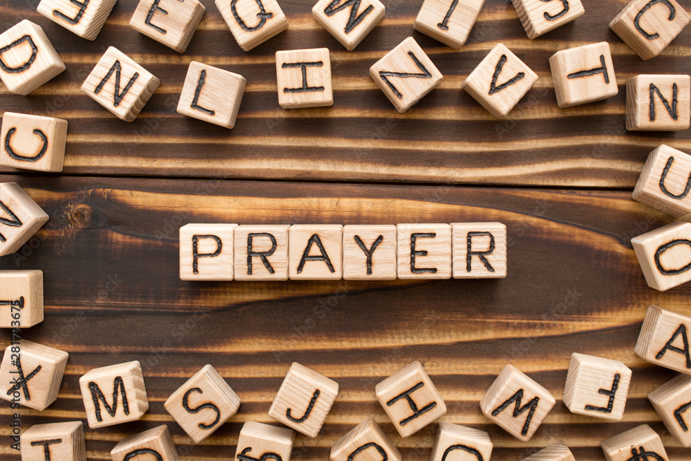 Prayer - word from wooden blocks with letters, speaking to God concept, random letters around, top view on wooden background