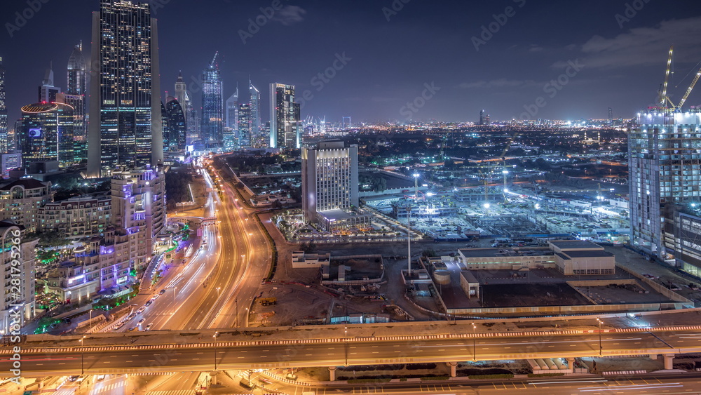 Fototapeta premium Construction activity in Dubai downtown with cranes and workers night timelapse, UAE.