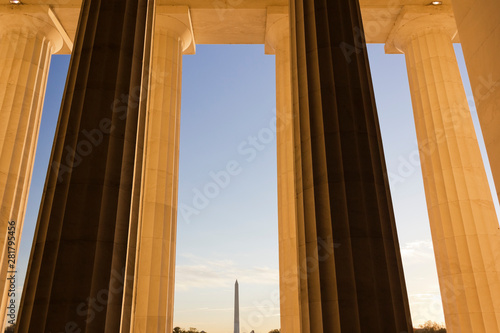Early morning sunlight shining on the colossal Doric colonnade of the Abraham Lincoln Memorial with the Washington Monument in the distance, Washington DC