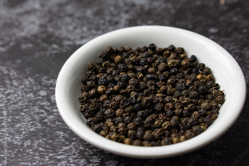Black pepper in a bowl on dark background. Black pepper in a bowl on dark background.