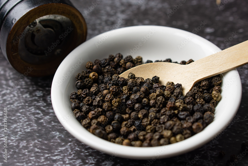 Black pepper in a bowl on dark background.