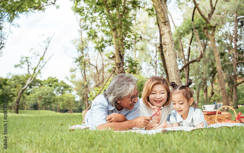 Naklejka premium Grandmother,Grandfather and grand daughter enjoying sunny garden holiday together, outdoors space, leisure lifestyle,happy teaching with flare light sky in park.