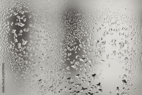 Closeup macro photo of water drops captured on glass window with dark background overlooking city street.