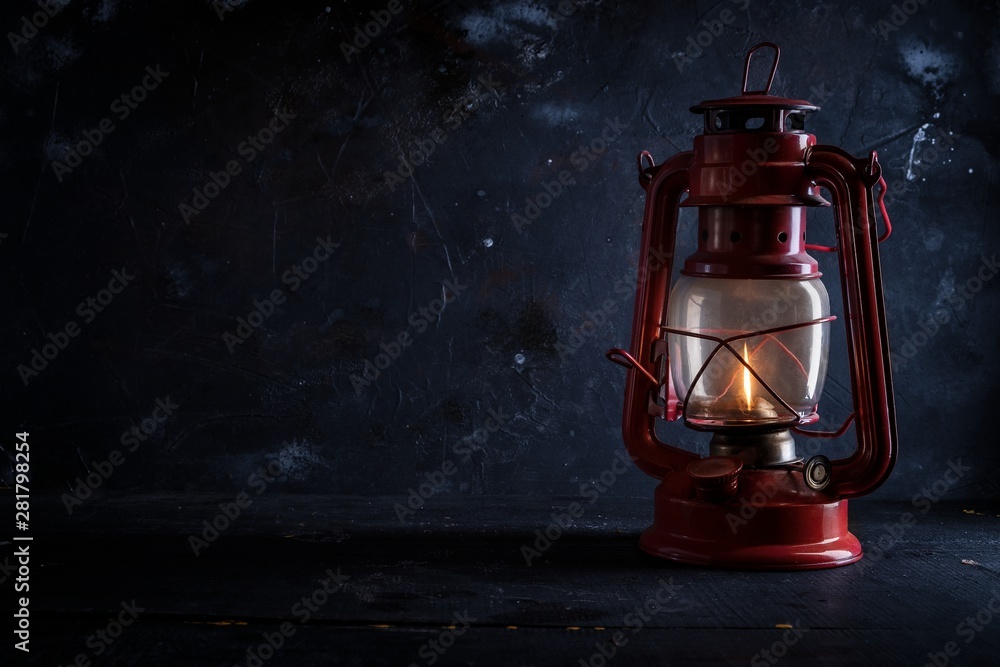 Red old kerosene lantern on dark background .