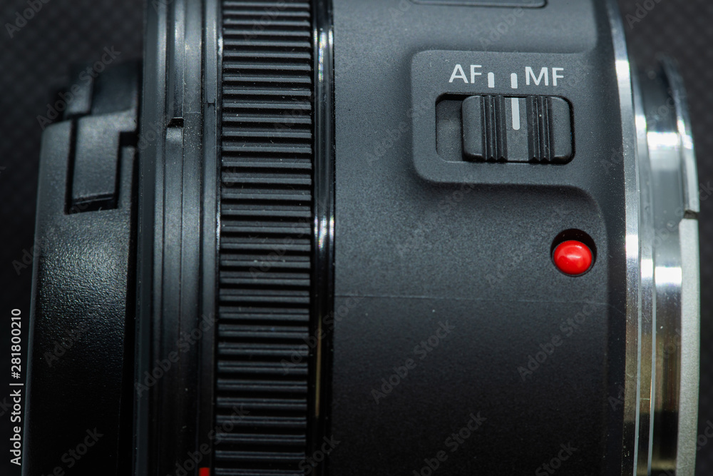 Obraz premium Macro closeup photo of lens to dslr camera on dark background view of red dot and silver extension ring and autofocus button.