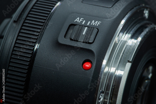 Macro closeup photo of lens to dslr camera on dark background view of red dot and silver extension ring and autofocus button. © Lukas
