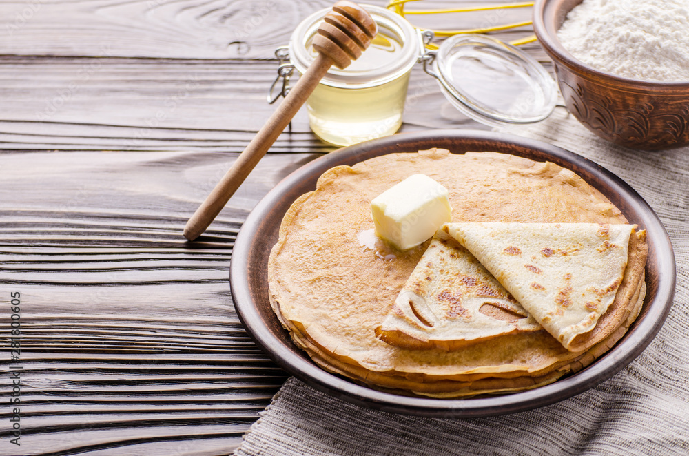 French crepes with butter flour and honey in ceramic dish on wooden kitchen table