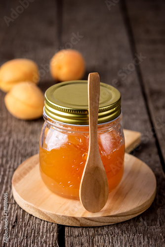 Glass Jar of Homemade Tasty Apricot Jam and Ripe Apricots on the Wooden Background Vertical