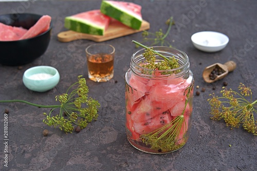 Cooking pickled watermelon in a glass jar on a dark concrete background. Canning, blanks. Watermelon Recipes