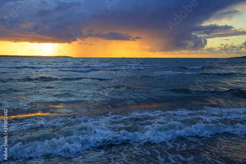 Dramatic sunset through a cloudy dark sky over the ocean.