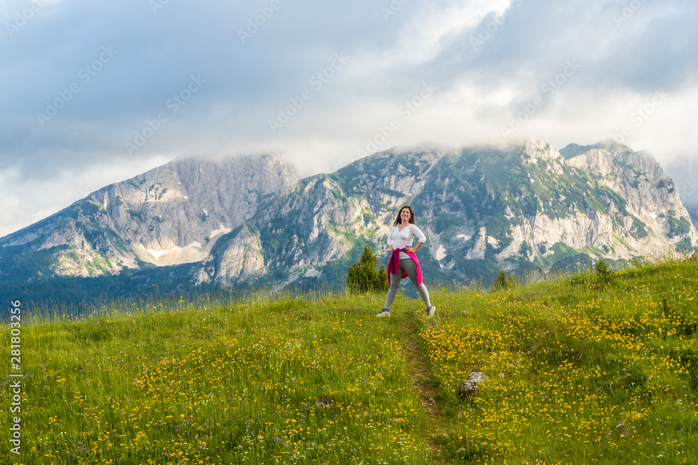 Obraz premium happy European girl stands on background of Montenegro mountains in Durmitor park, with copy space