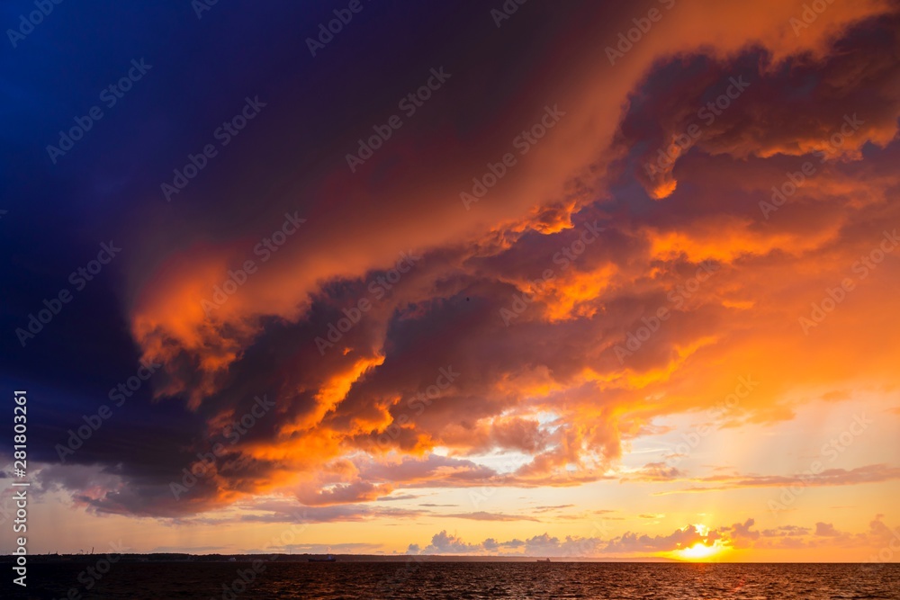 Dramatic sunset through a cloudy dark sky over the ocean.